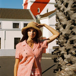 woman holds onto hat and looks at camera