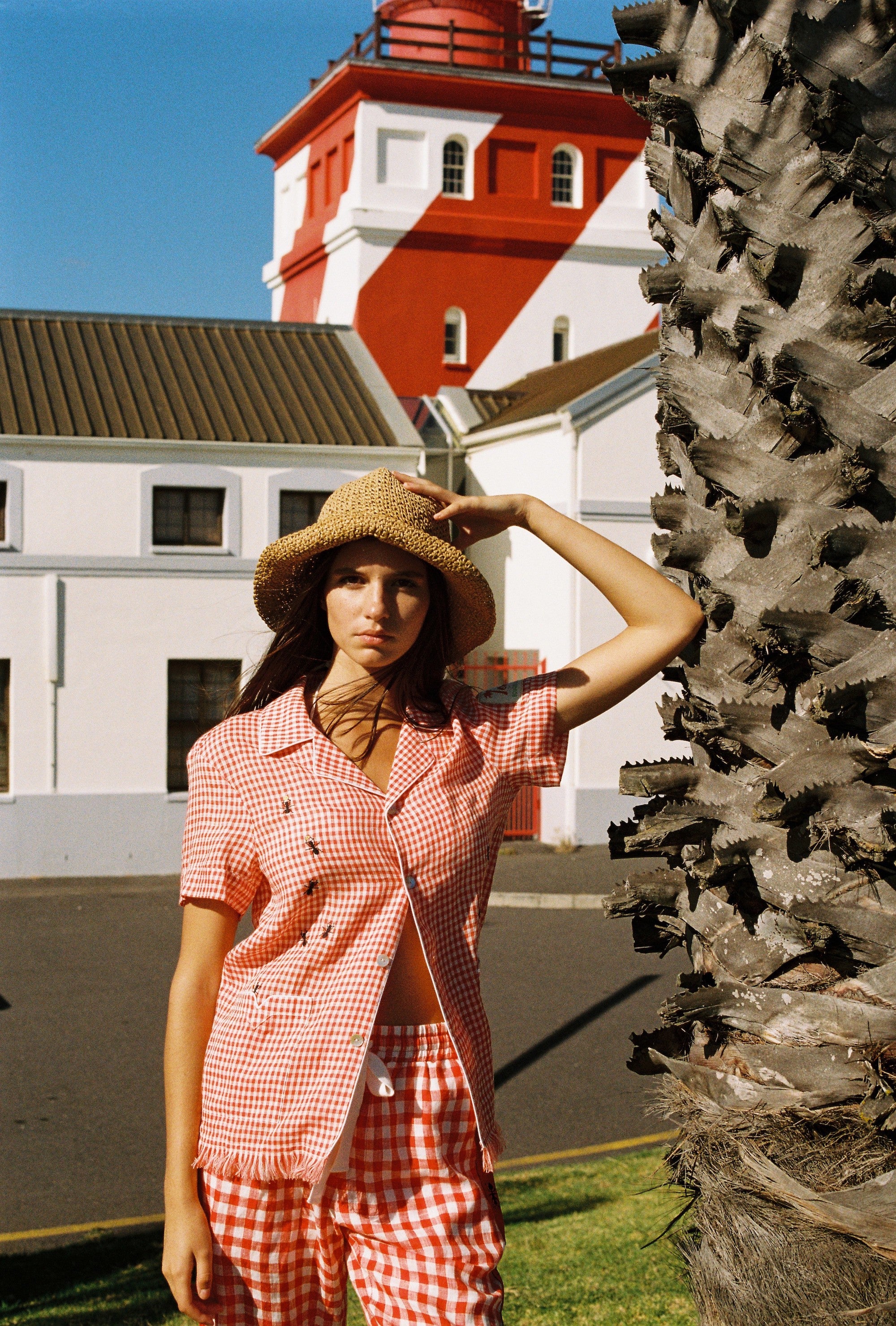 woman holds onto hat and looks at camera