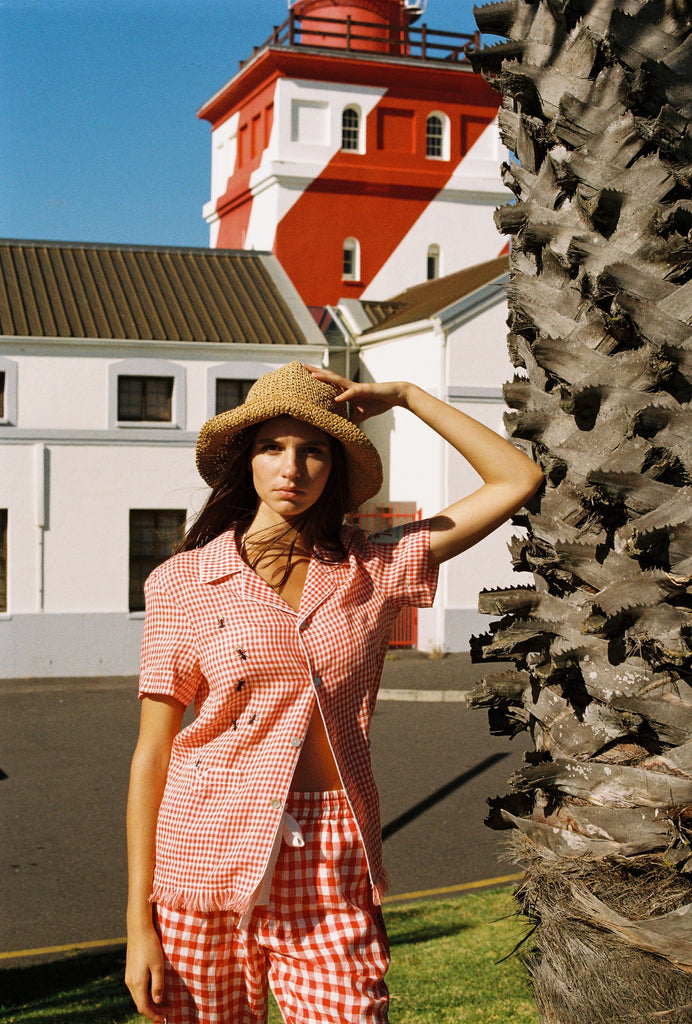 woman holds onto hat and looks at camera