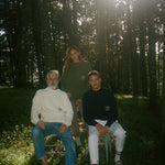 Woman, older and younger man sit together in the middle of a forest