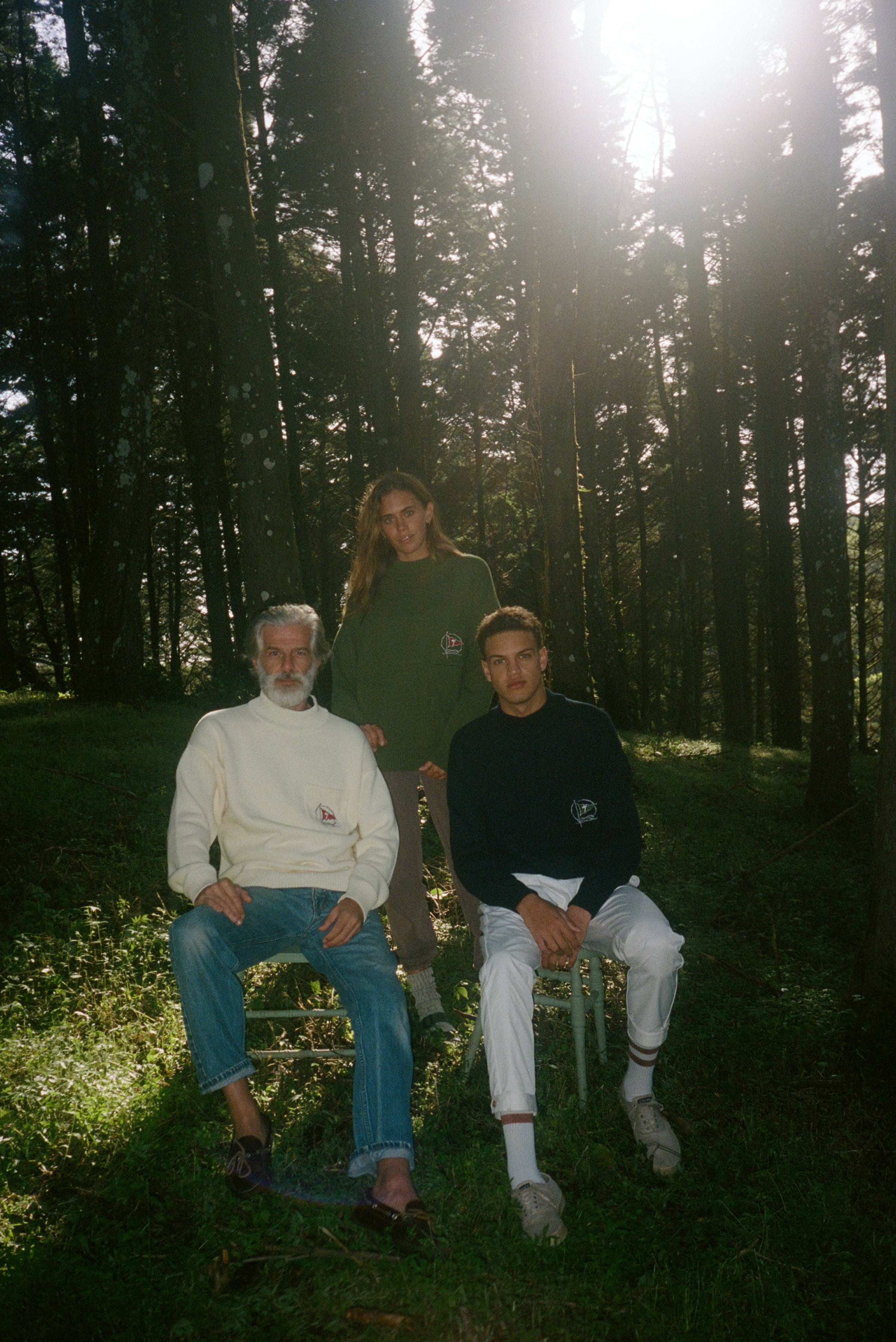 Woman, older and younger man sit together in the middle of a forest