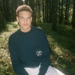 Man sits in forest looking straight at camera
