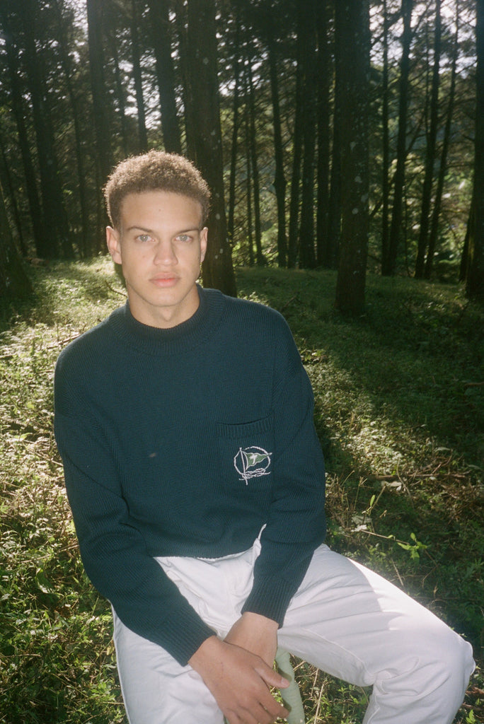 Man sits in forest looking straight at camera