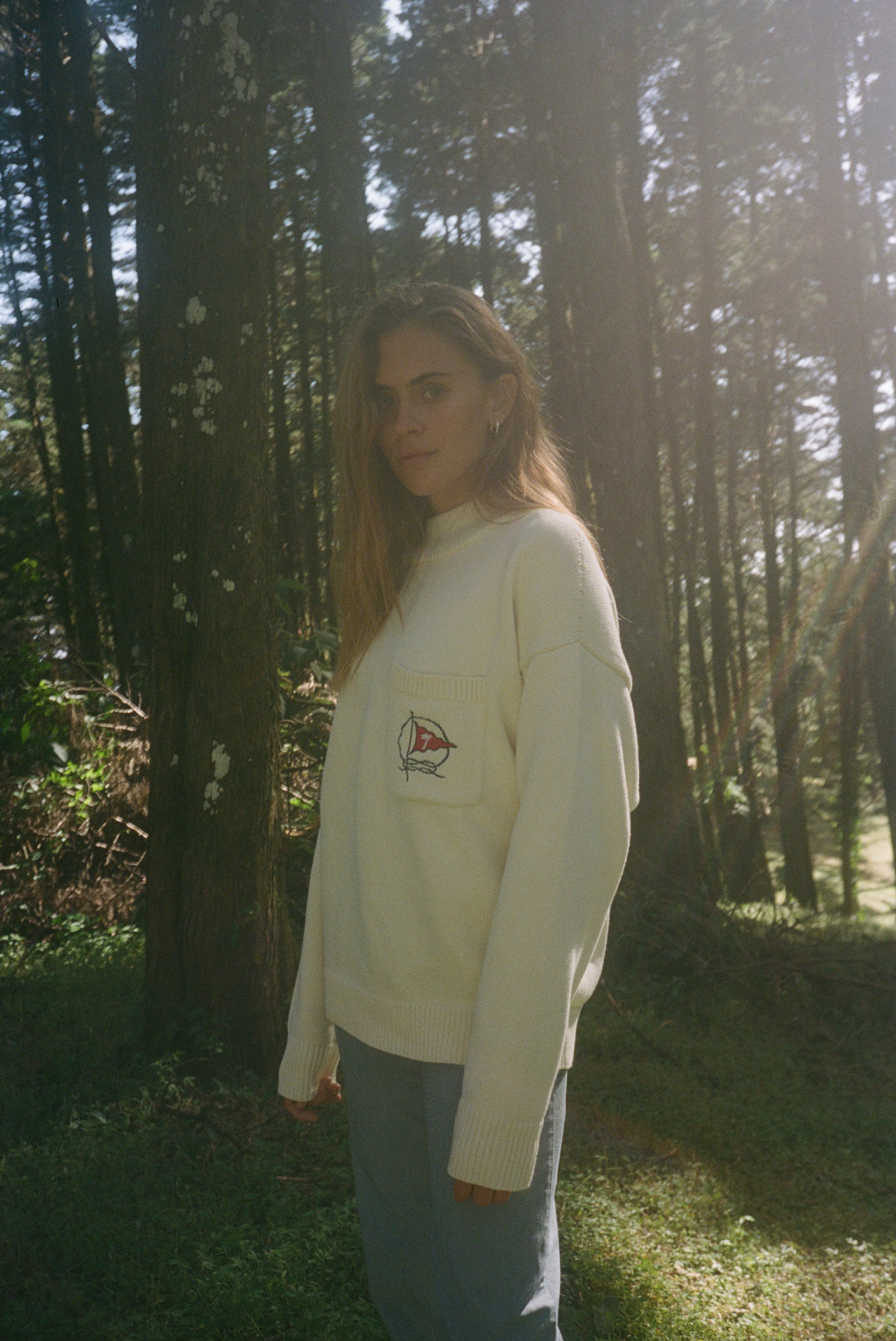 Wman stands side on while gazing at camera