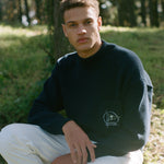 Man sits on stool in forest gazing at camera
