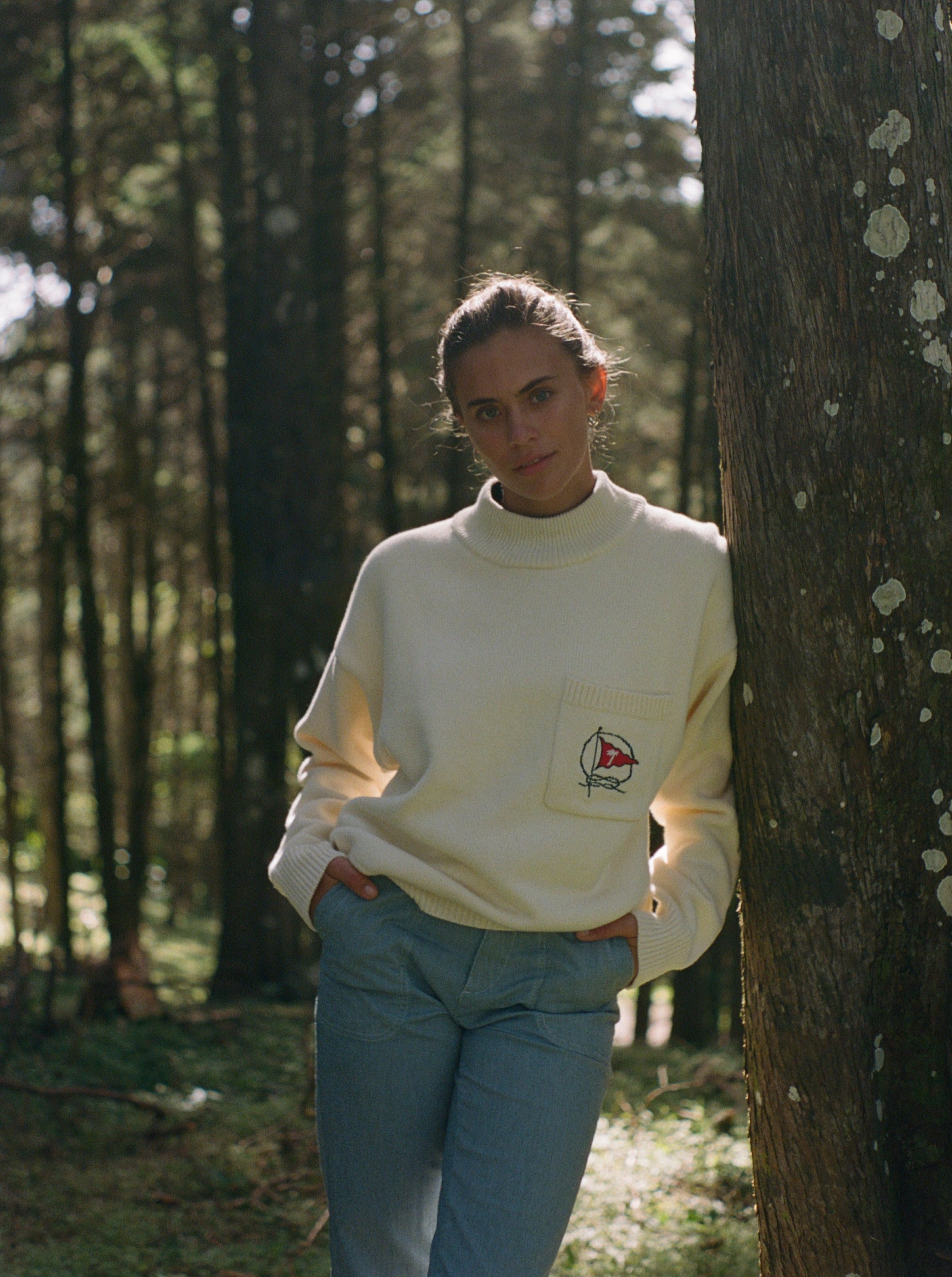 Woman leans against tree and gazes at camera