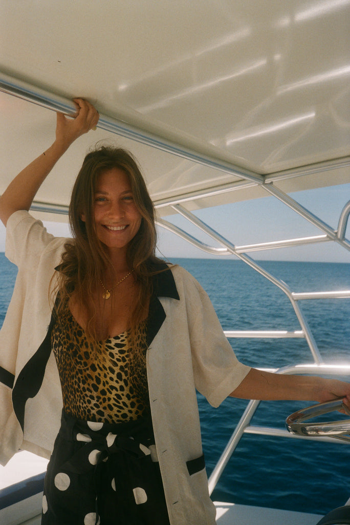 Female model wearing the cabana unbuttoned and billowy over a cheetah swimsuit and polka dot pants