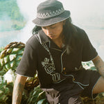 man looks downward in shirt and bucket hat