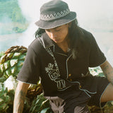 man looks downward in shirt and bucket hat