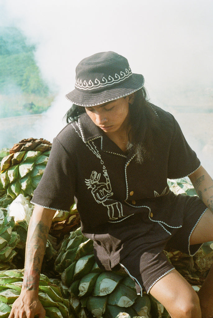 man looks downward in shirt and bucket hat