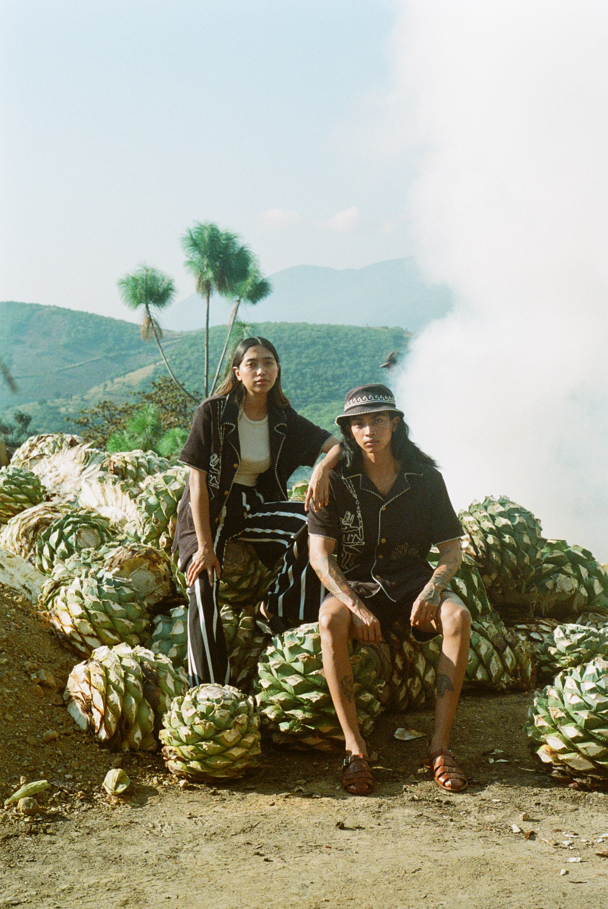 man and woman sit wearing agua magica cabanas