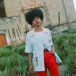 Woman wearing linen Tombolo Martini shirt with one button done, gazing at camera