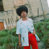 Woman wearing linen Tombolo Martini shirt with one button done, gazing at camera