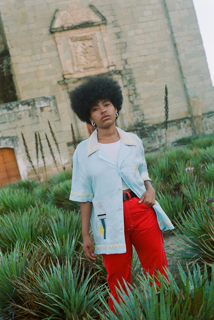 Woman wearing linen Tombolo Martini shirt with one button done, gazing at camera