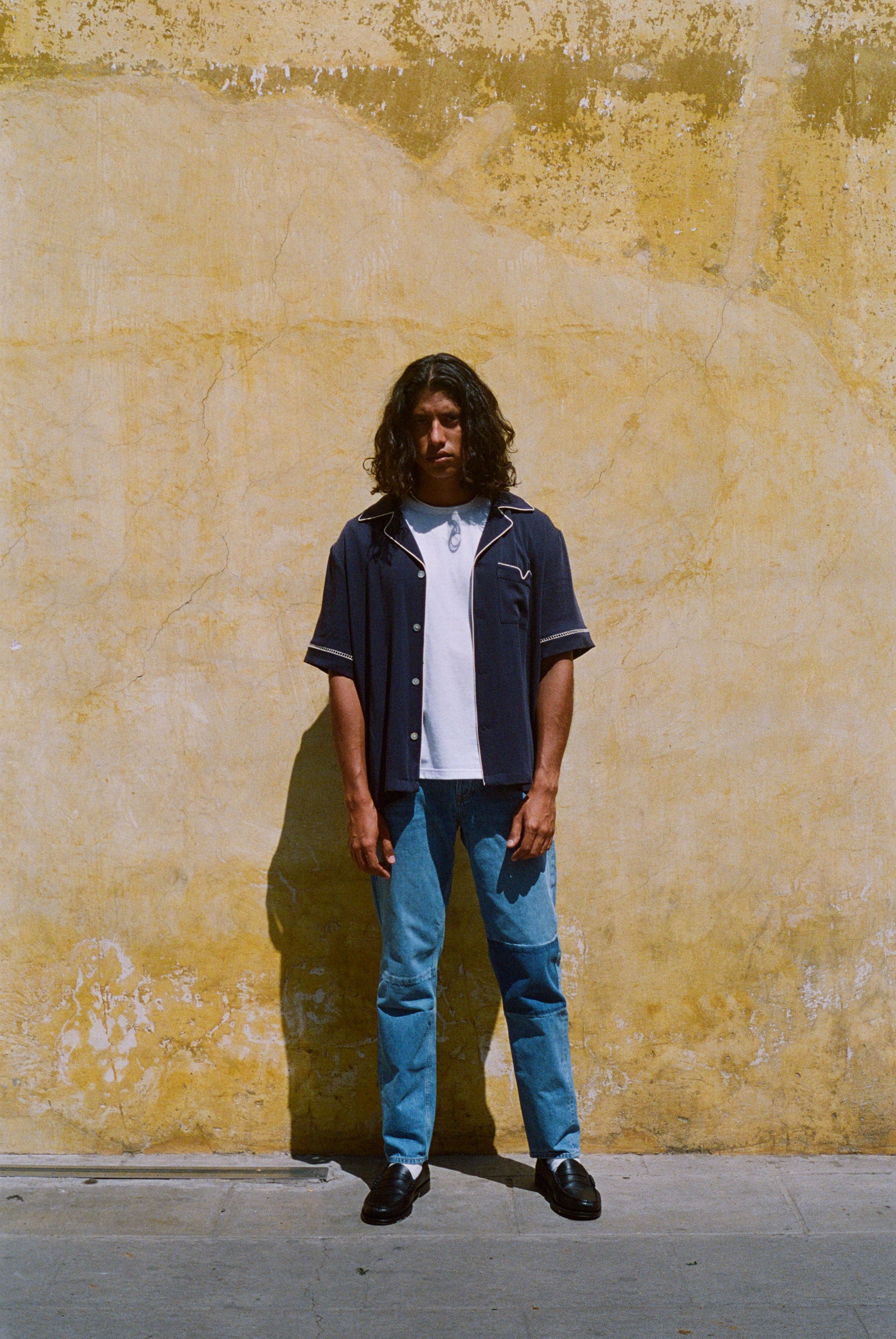 Male model wearing navy cabrisa unbuttoned standing on a wall