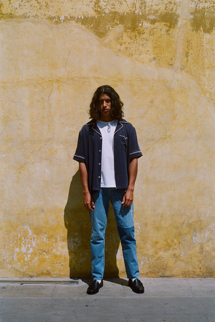 Male model wearing navy cabrisa unbuttoned standing on a wall