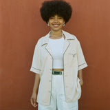 female model wearing cabrisa unbuttoned with white pants and a green belt