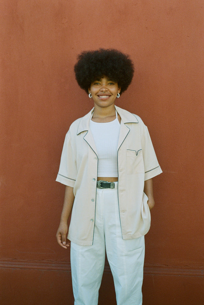 female model wearing cabrisa unbuttoned with white pants and a green belt