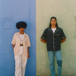 female and male models wearing navy and parchment cabrisas standing on a wall