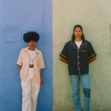 female and male models wearing navy and parchment cabrisas standing on a wall