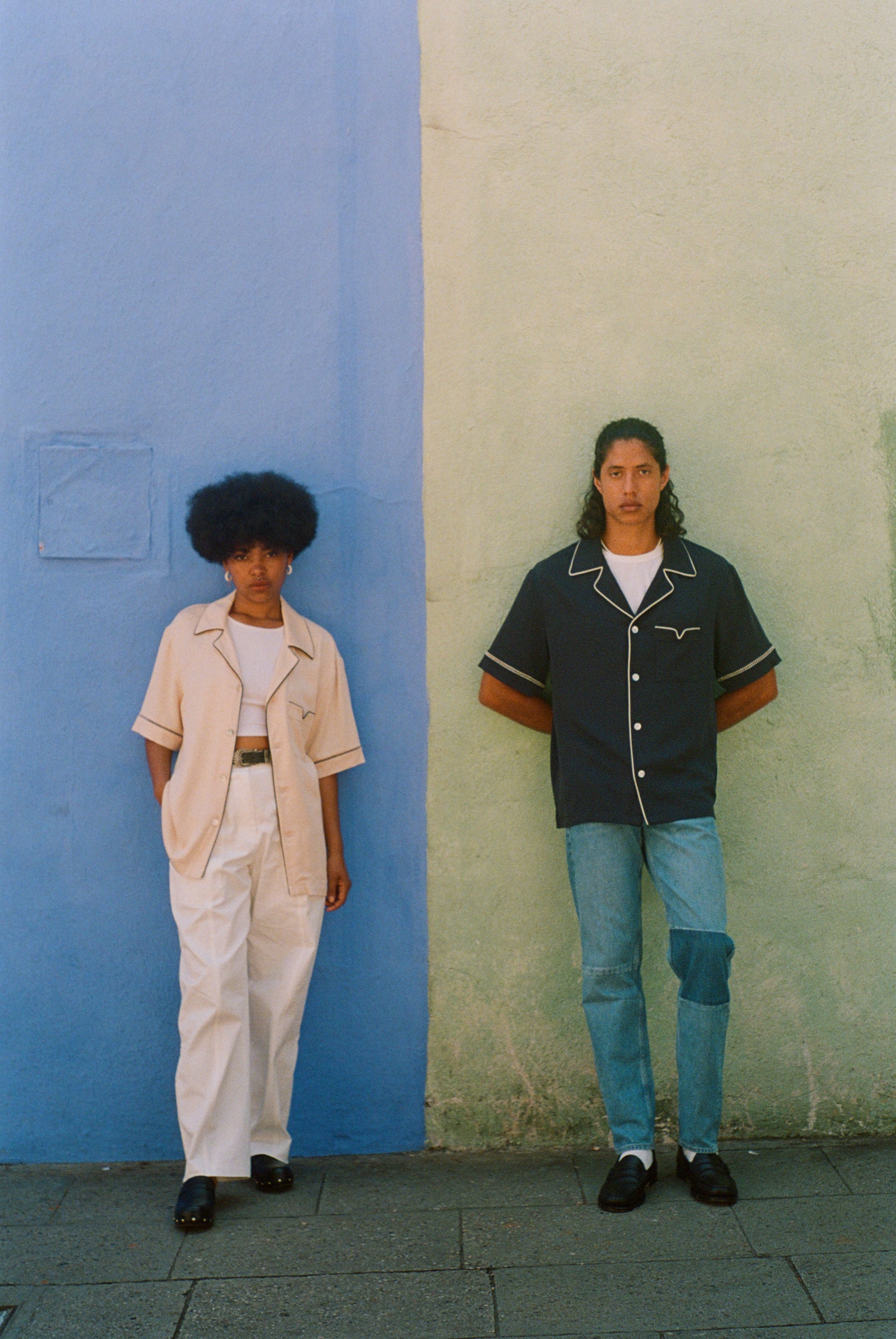 female and male models wearing navy and parchment cabrisas standing on a wall