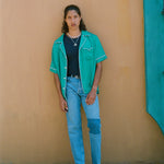male model wearing shirt standing against wooden wall
