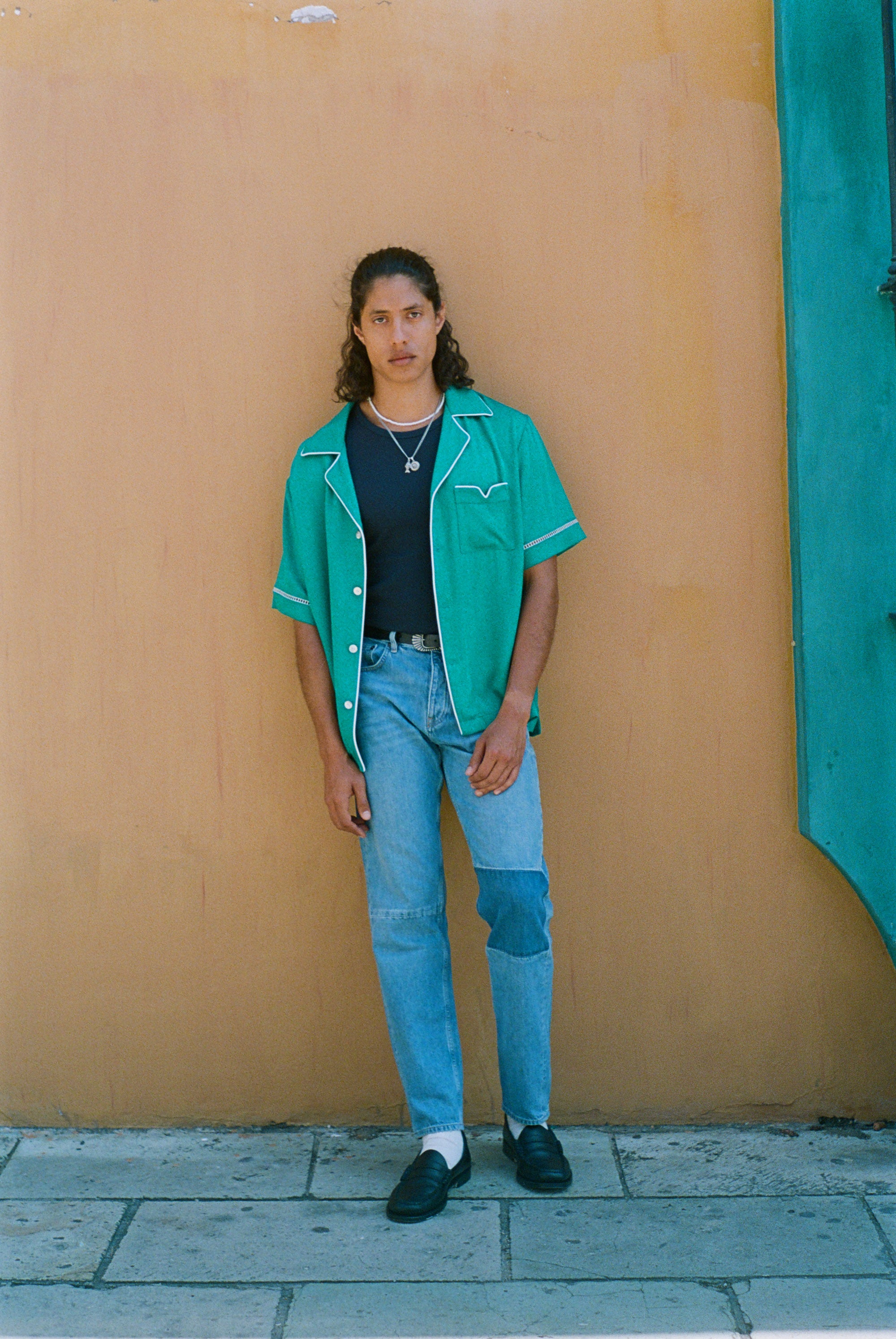 male model wearing shirt standing against wooden wall