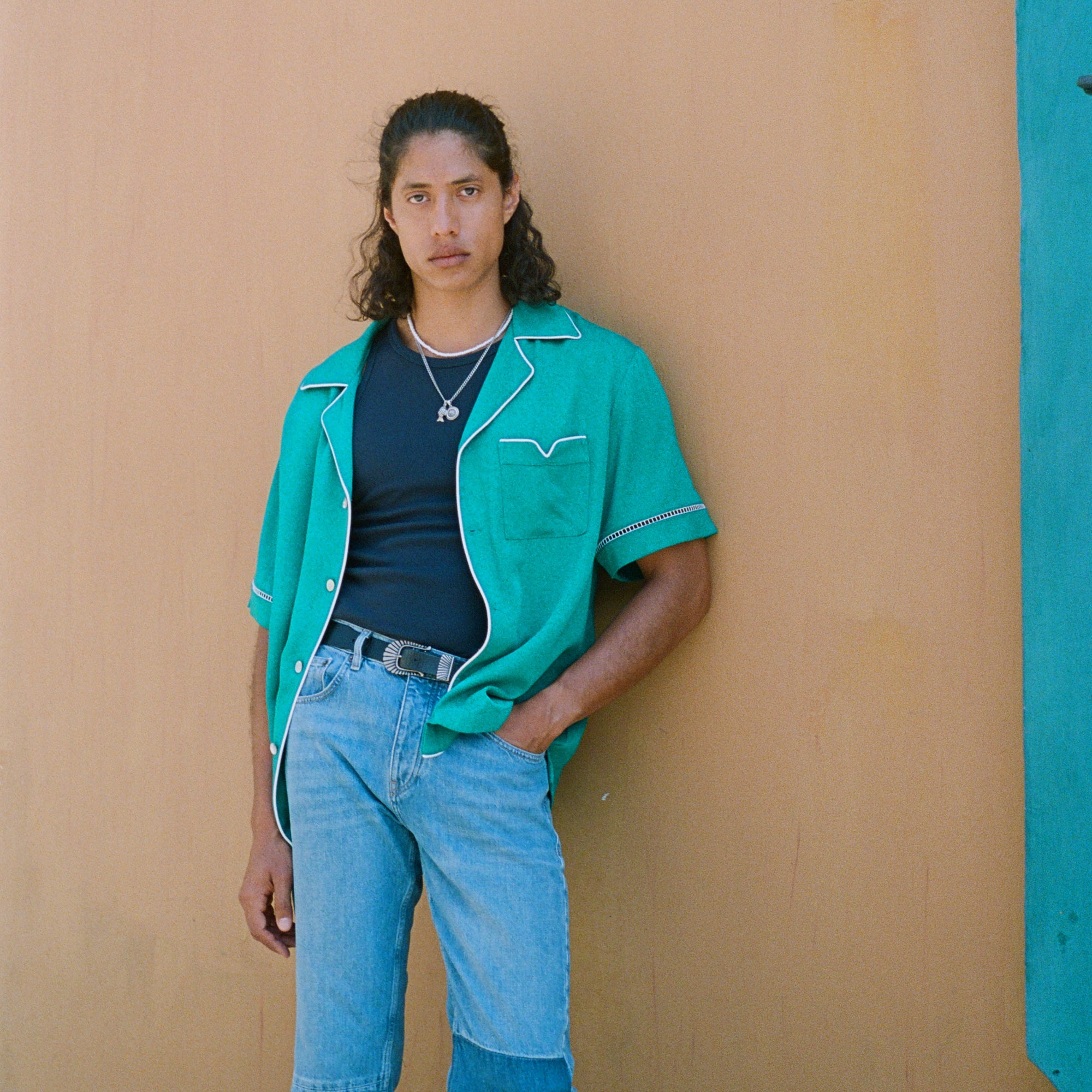 Male model wearing teal cabrisa top with hand tucked into his jeans pocket