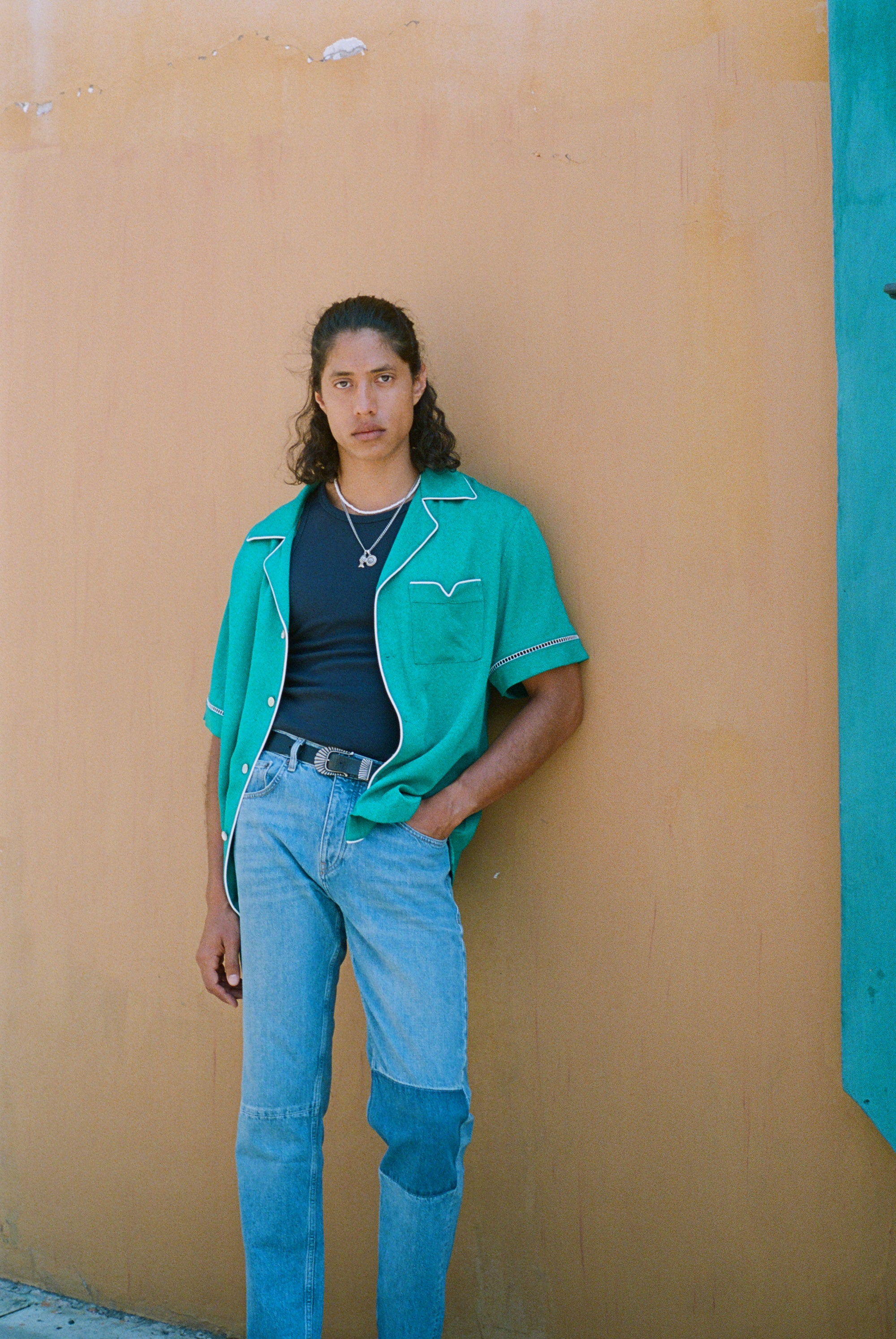 Male model wearing teal cabrisa top with hand tucked into his jeans pocket