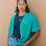 Male model in teal cabrisa opened over a black wife beater