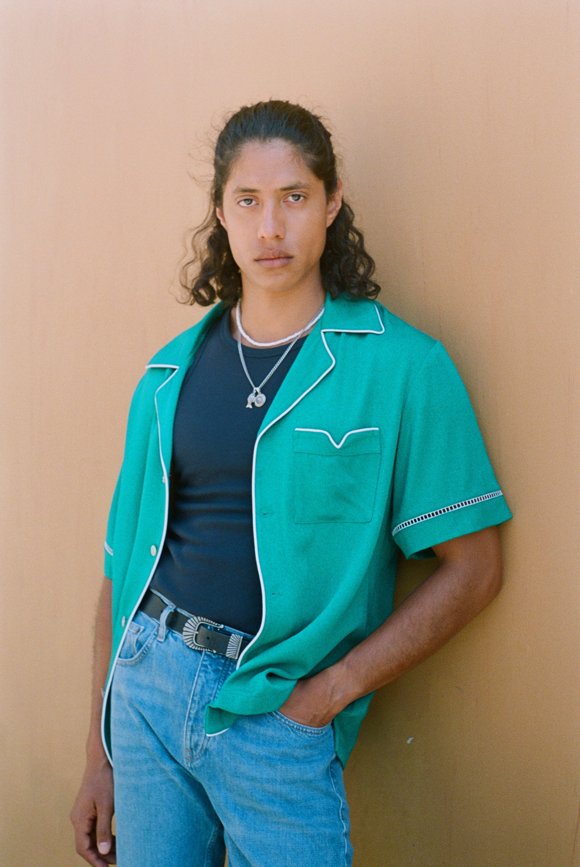 Male model in teal cabrisa opened over a black wife beater