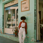 Female model in shirt next to a teal store