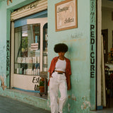 Female model in shirt next to a teal store
