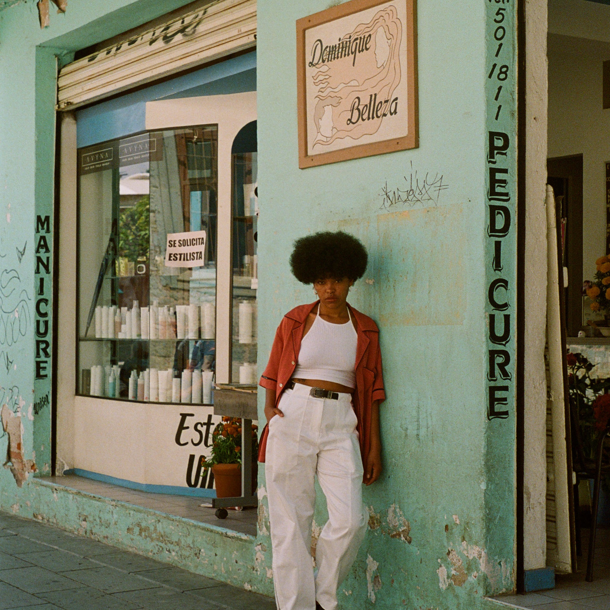 Female model in shirt next to a teal store