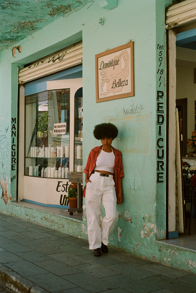 Female model in shirt next to a teal store