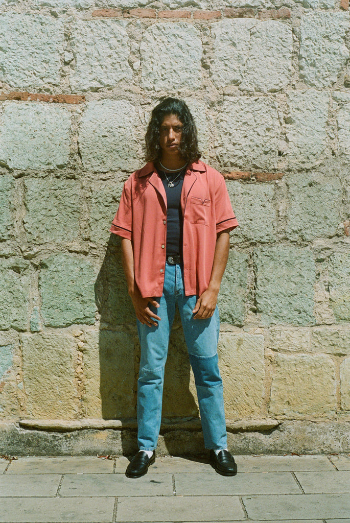 Male model wearing shirt open over a black tank and jeans