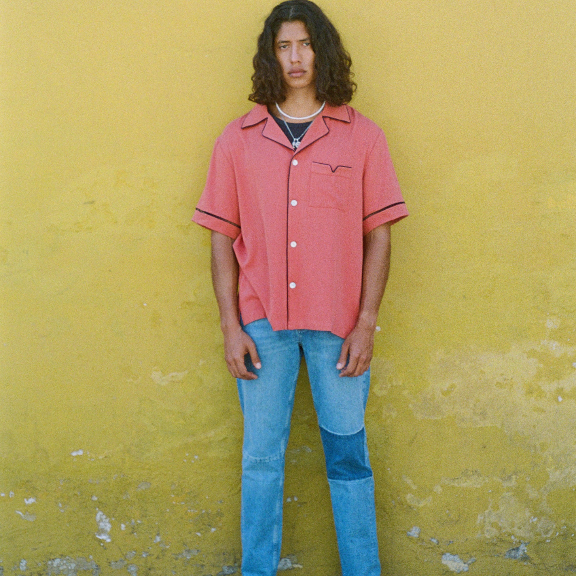 Male model in shirt with jeans on a yellow wall