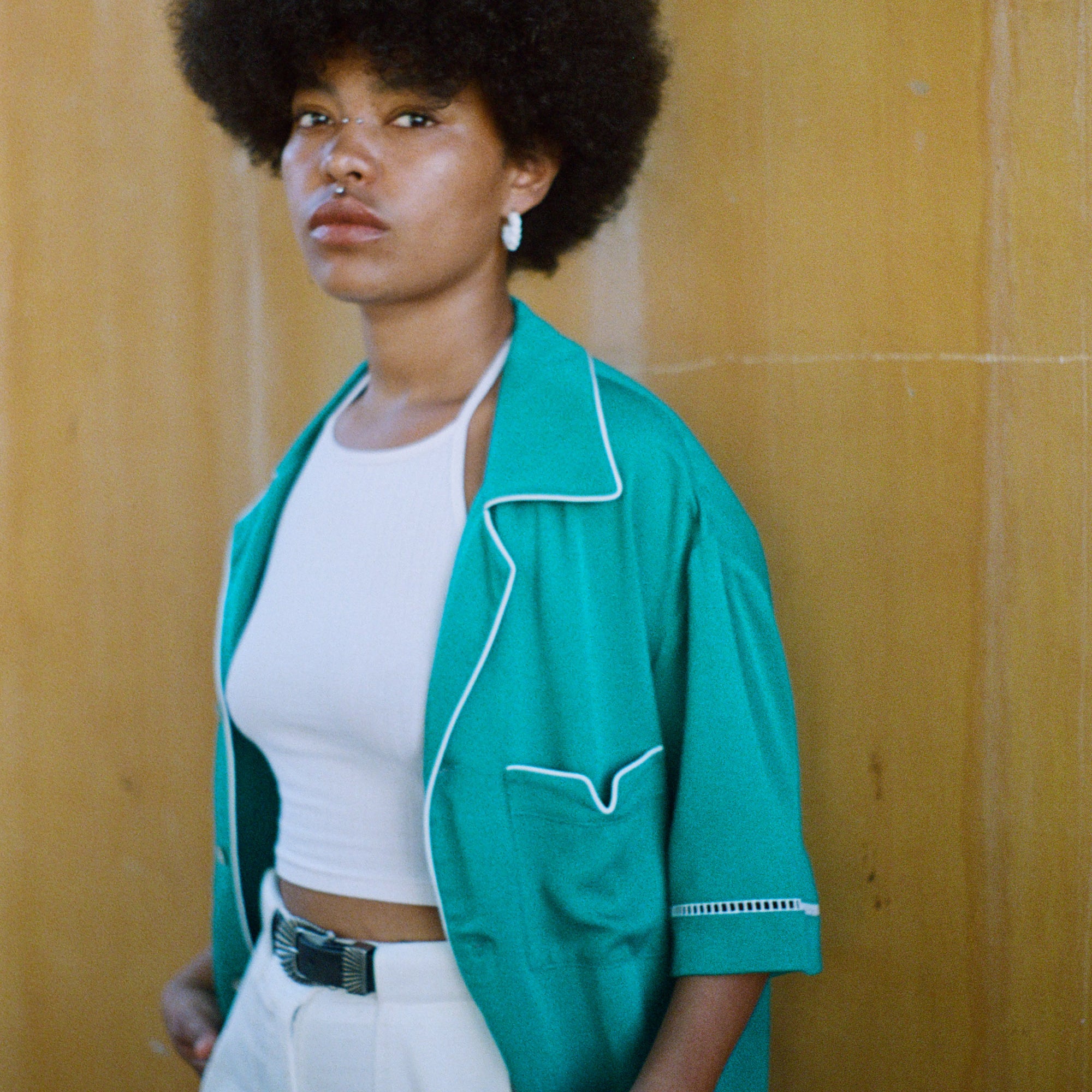 Female model wearing teal cabrisa over a white tank top and white pants