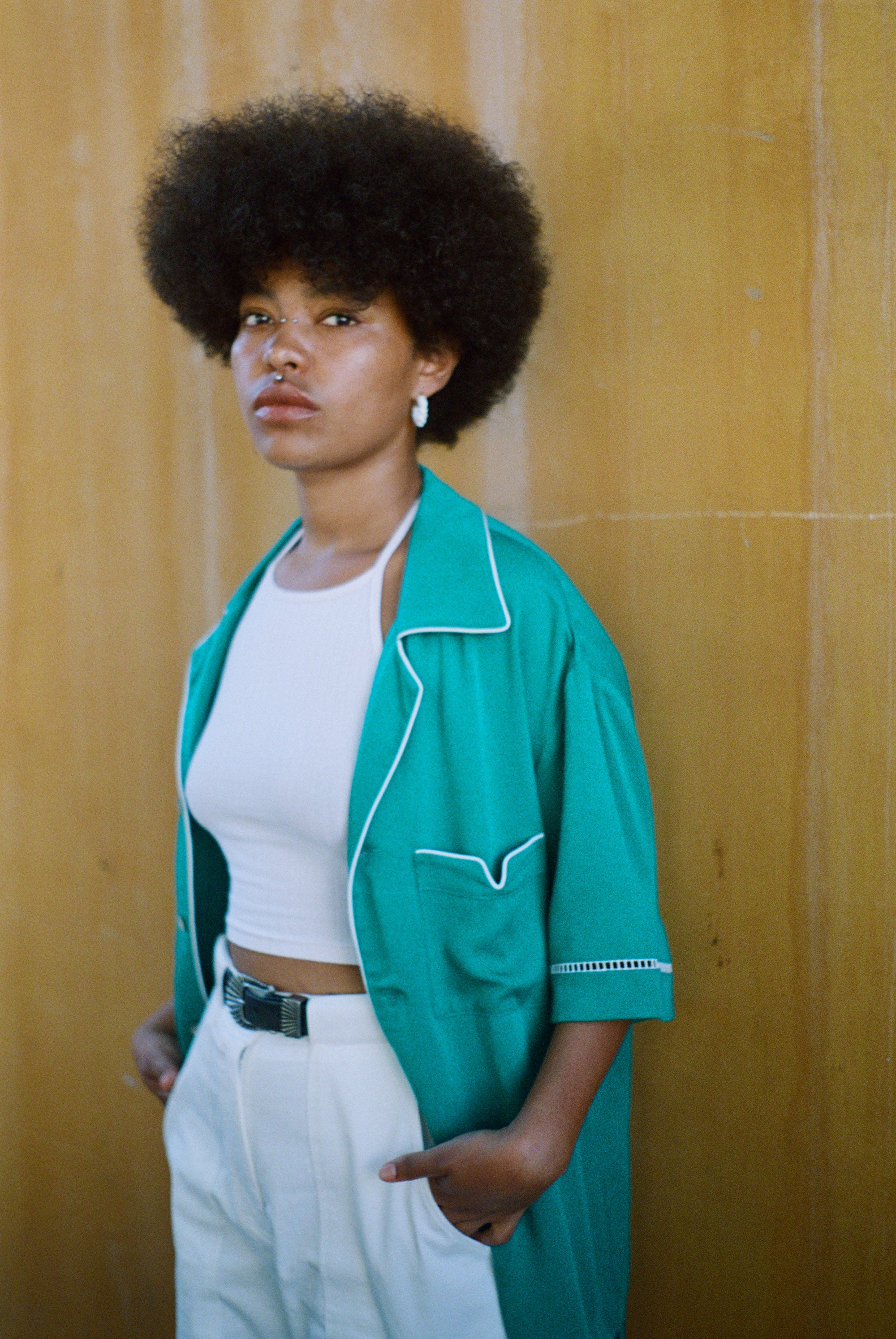 Female model wearing teal cabrisa over a white tank top and white pants