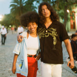 Man puts arm around woman walking through a town square while wearing Big Brut cabana shirt