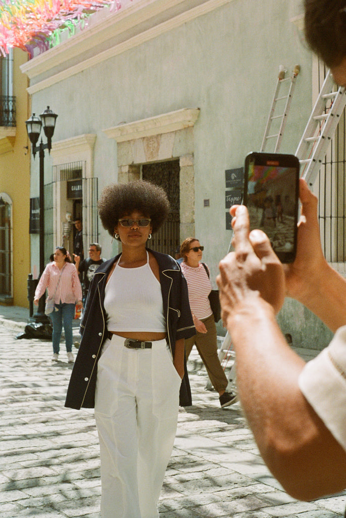 Female model wearing navy cabrisa unbuttoned on a street being photographed with an iPhone