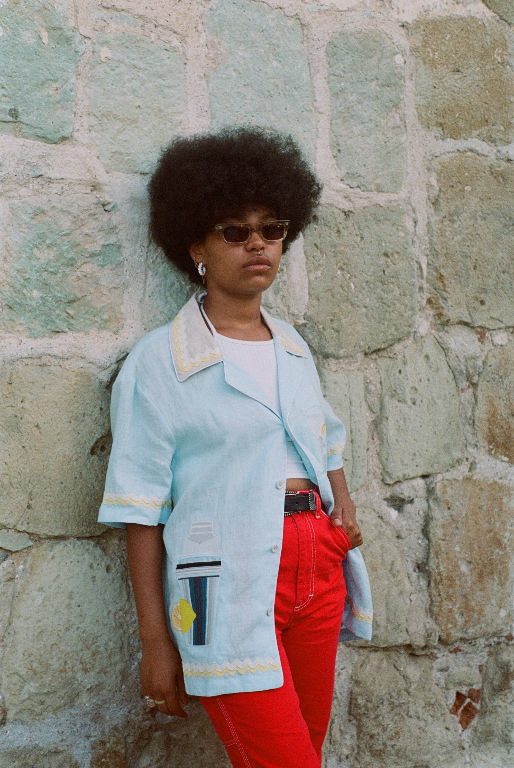Woman leaning against wall posing in Tombolo linen shirt