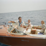 Boat captain wearing pop over with one other male and female model in boat
