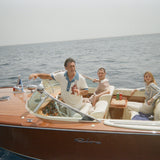 Boat captain wearing pop over with one other male and female model in boat