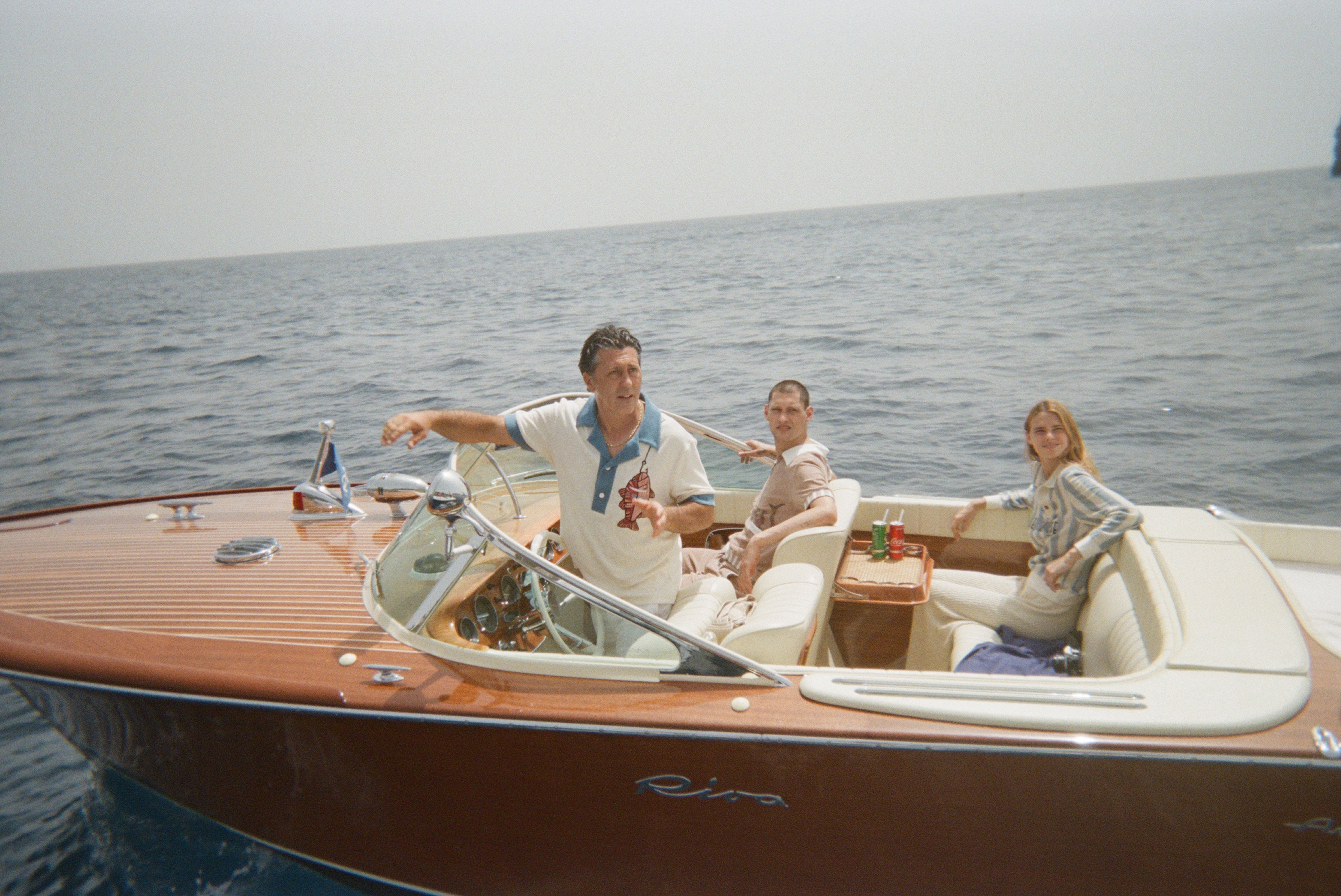 Boat captain wearing pop over with one other male and female model in boat