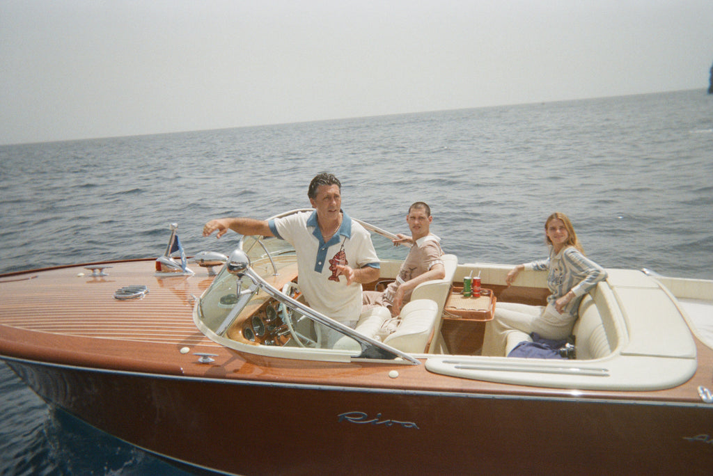 Boat captain wearing pop over with one other male and female model in boat