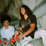 Man and woman sit on bench as man pops champagne bottle