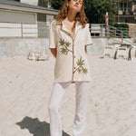 woman puts both arms behind her back standing on the beach 