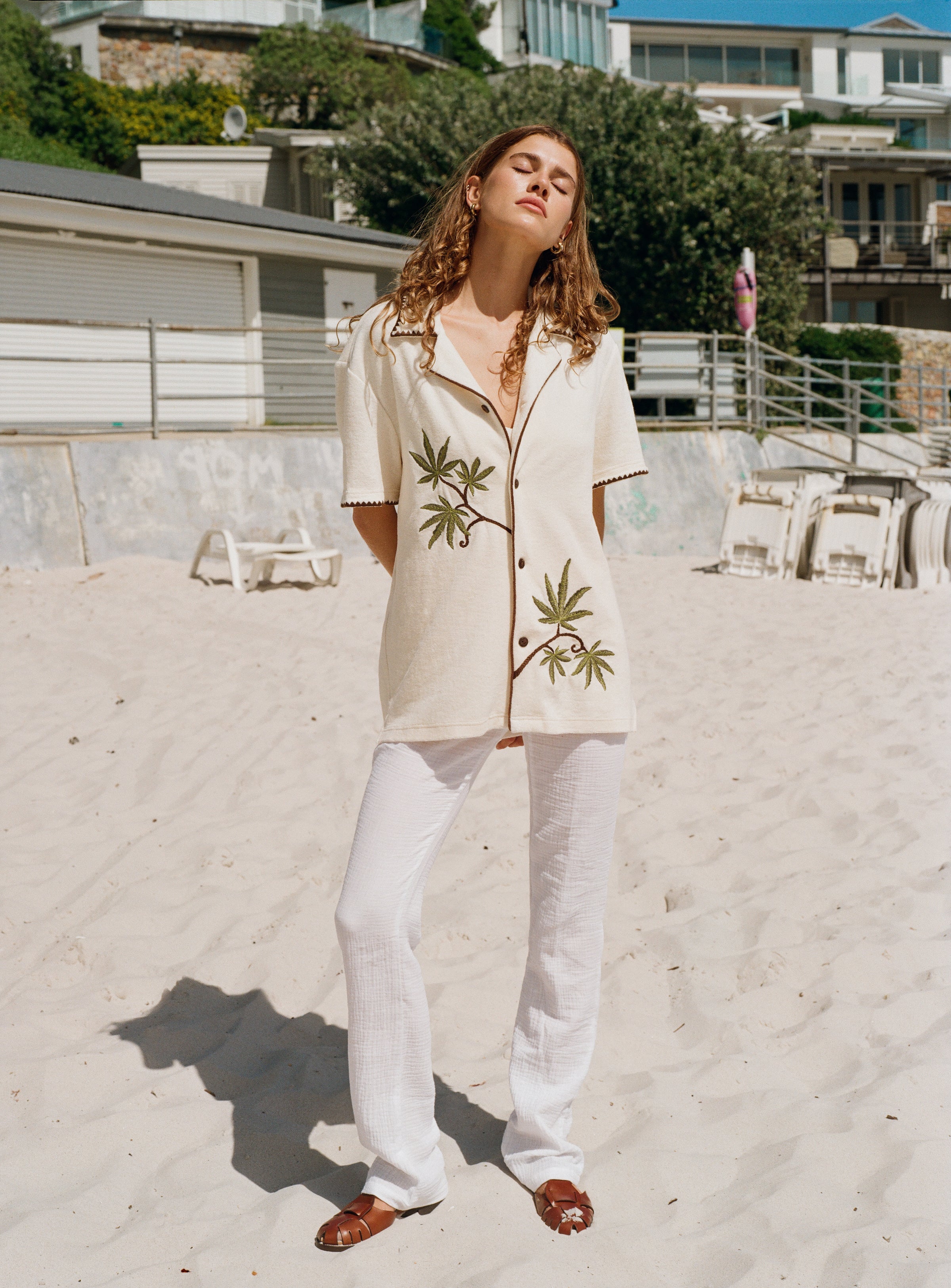 woman puts both arms behind her back standing on the beach 