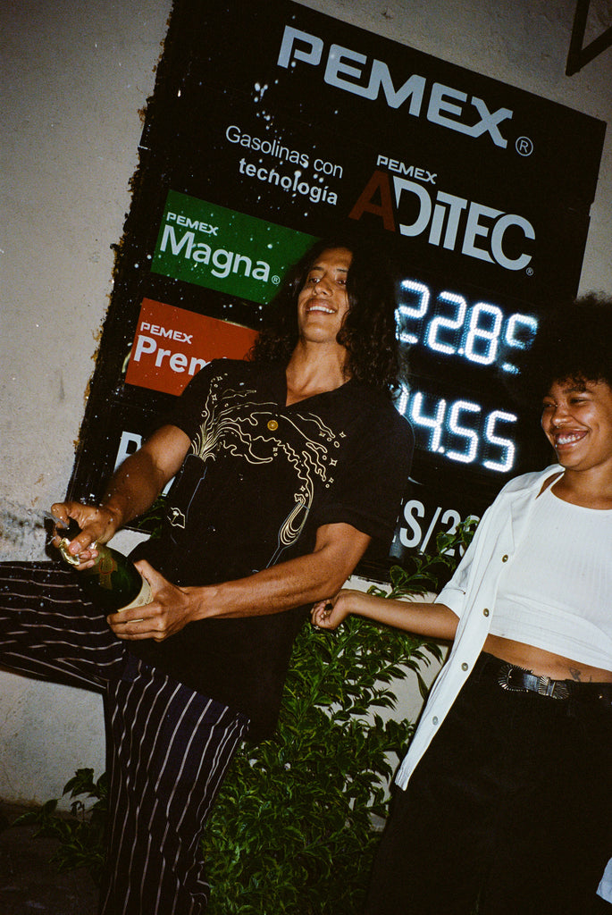 Model wearing big brut shirt popping top off of real champagne bottle